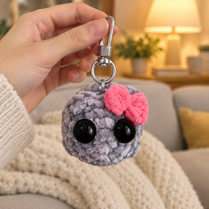 Hand holding the Sad Hamster keychain in a cozy living room
